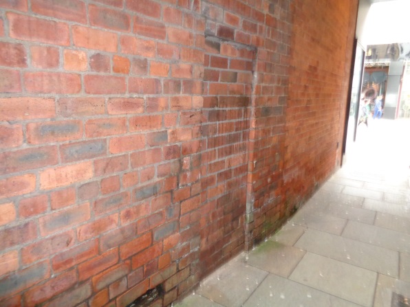 A view of the area with the location of the Bench Mark (just down and right of the bricked up door/cellar or whatever) near the start of the Angel Inn Yard off Briggate, Leeds (taken June 30 2016).